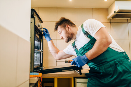 Technician repairing turntable and magnetron on a built-in microwave in Los Angeles